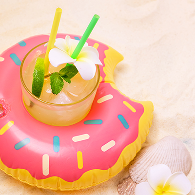 Pool Toy Ring with Glass of Cold Cocktail Background with Inflatable Donut Summer vibes Concept Vertical