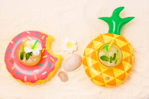Pool Toy Ring with Glass of Cold Cocktail Background with Inflatable Flamingo and Donut Summer Pool Toy Ring with Glass of Cold Cocktail Background with Inflatable Flamingo and Donut Summer